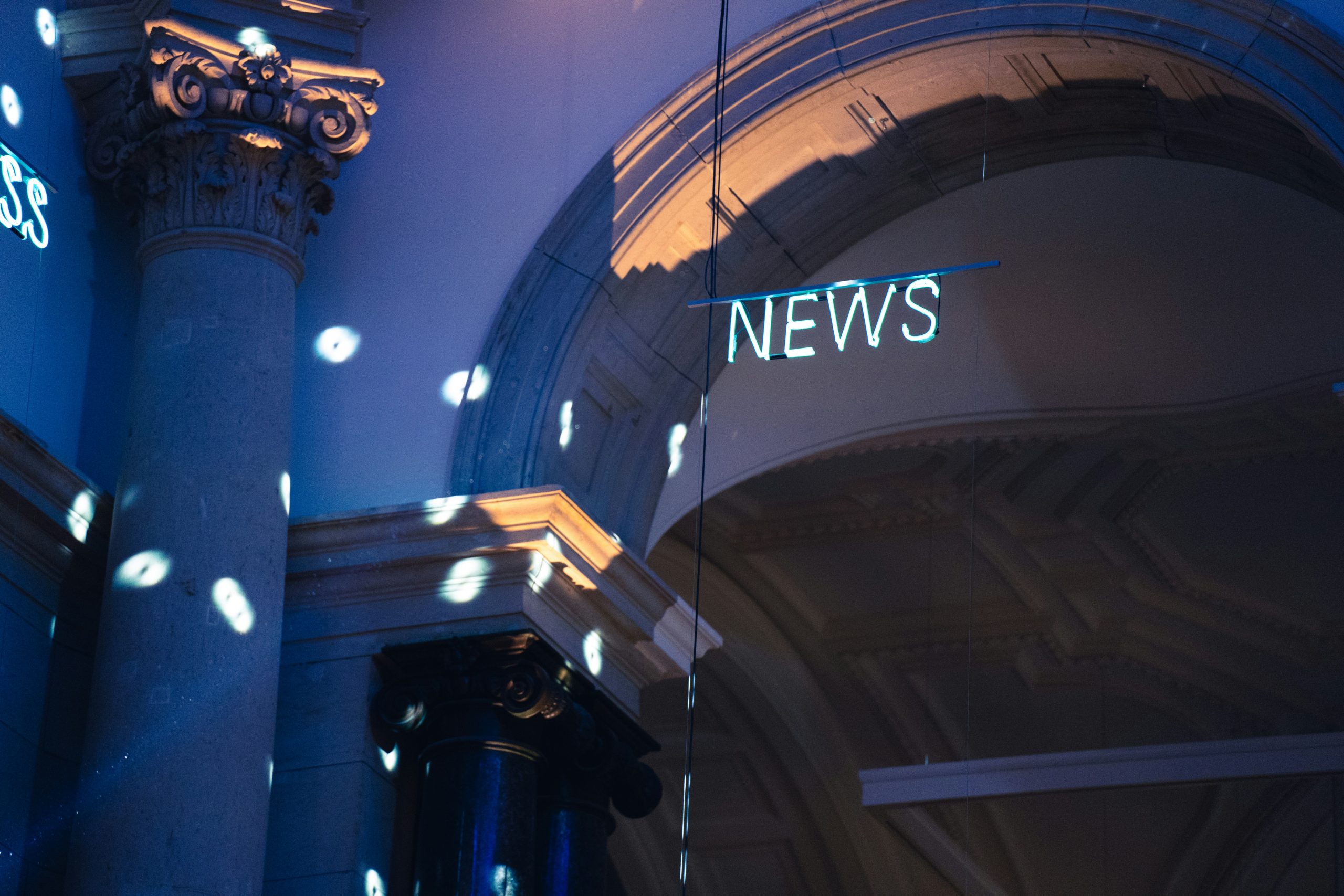 Interior of a building with the word News lit on the wall